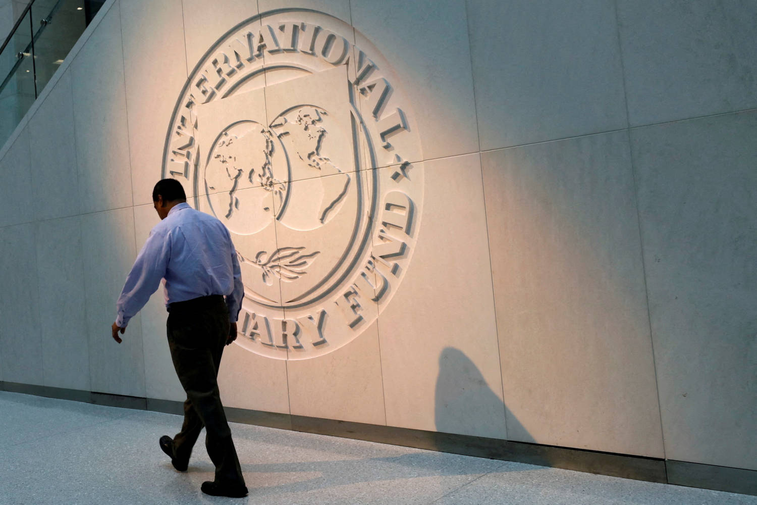 File Photo: Man Walks Past The Imf Logo At Hq In Washington