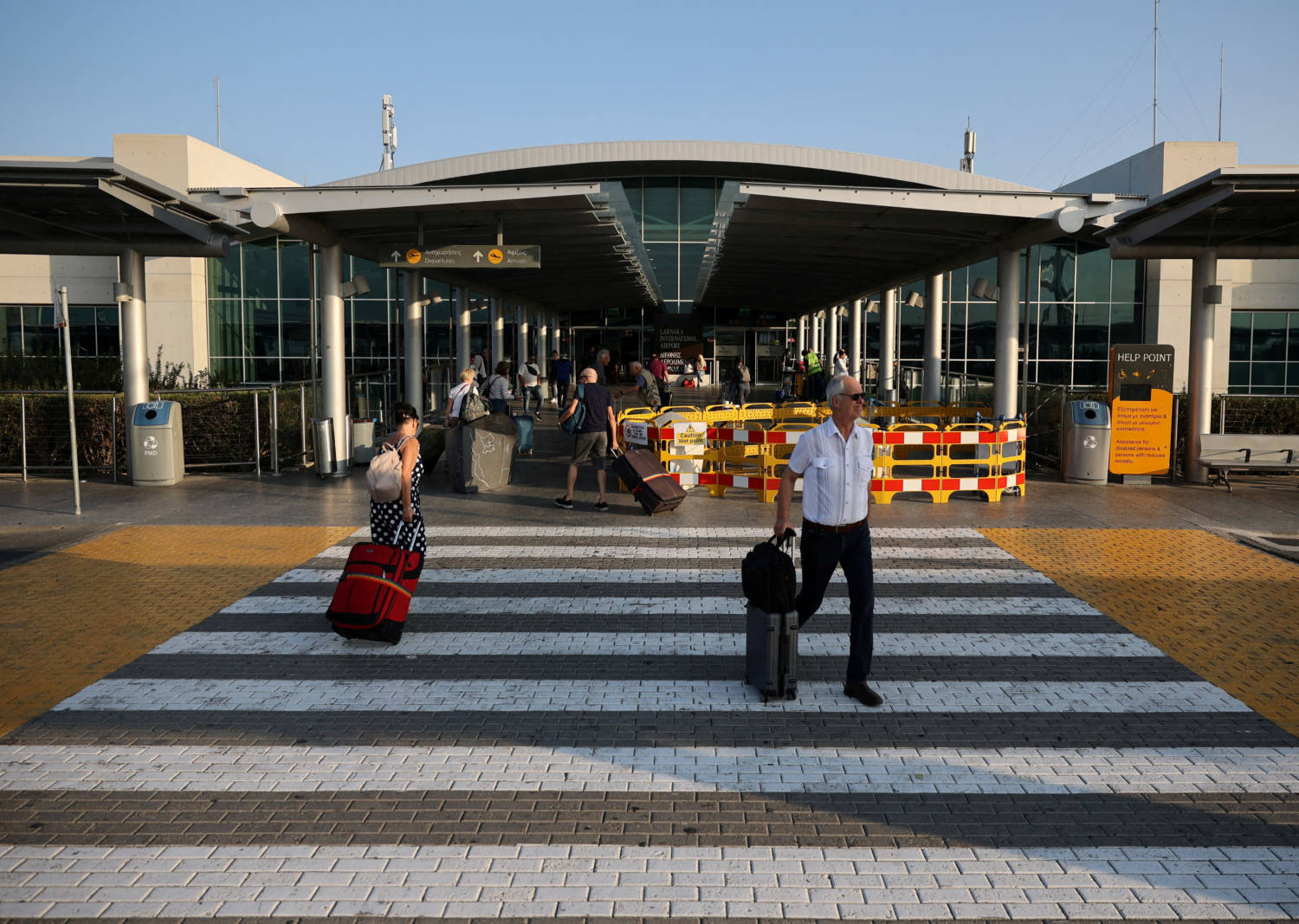 File Photo: People Walk With Their Luggage Outside Larnaca International Airport, In Larnaca