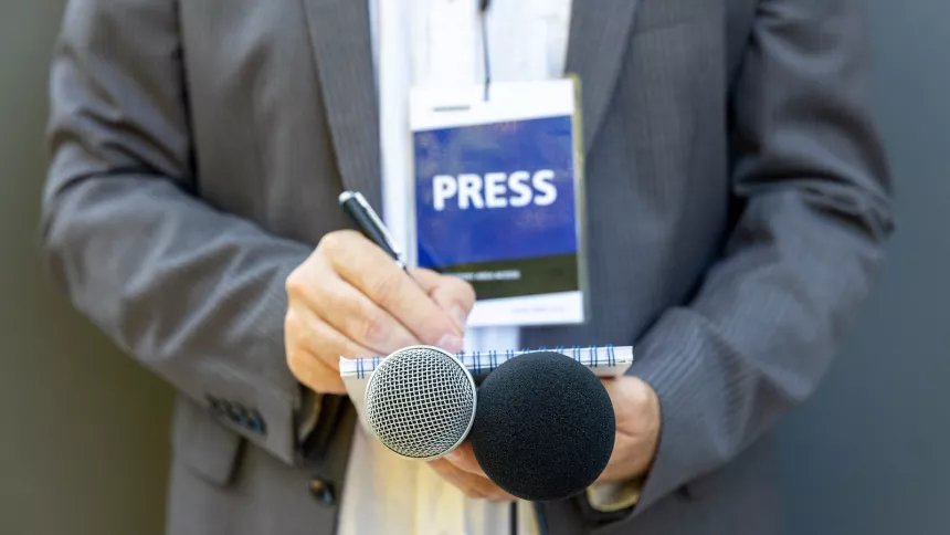 Reporter With Press Badge Taking Notes Shutterstock 1808083621